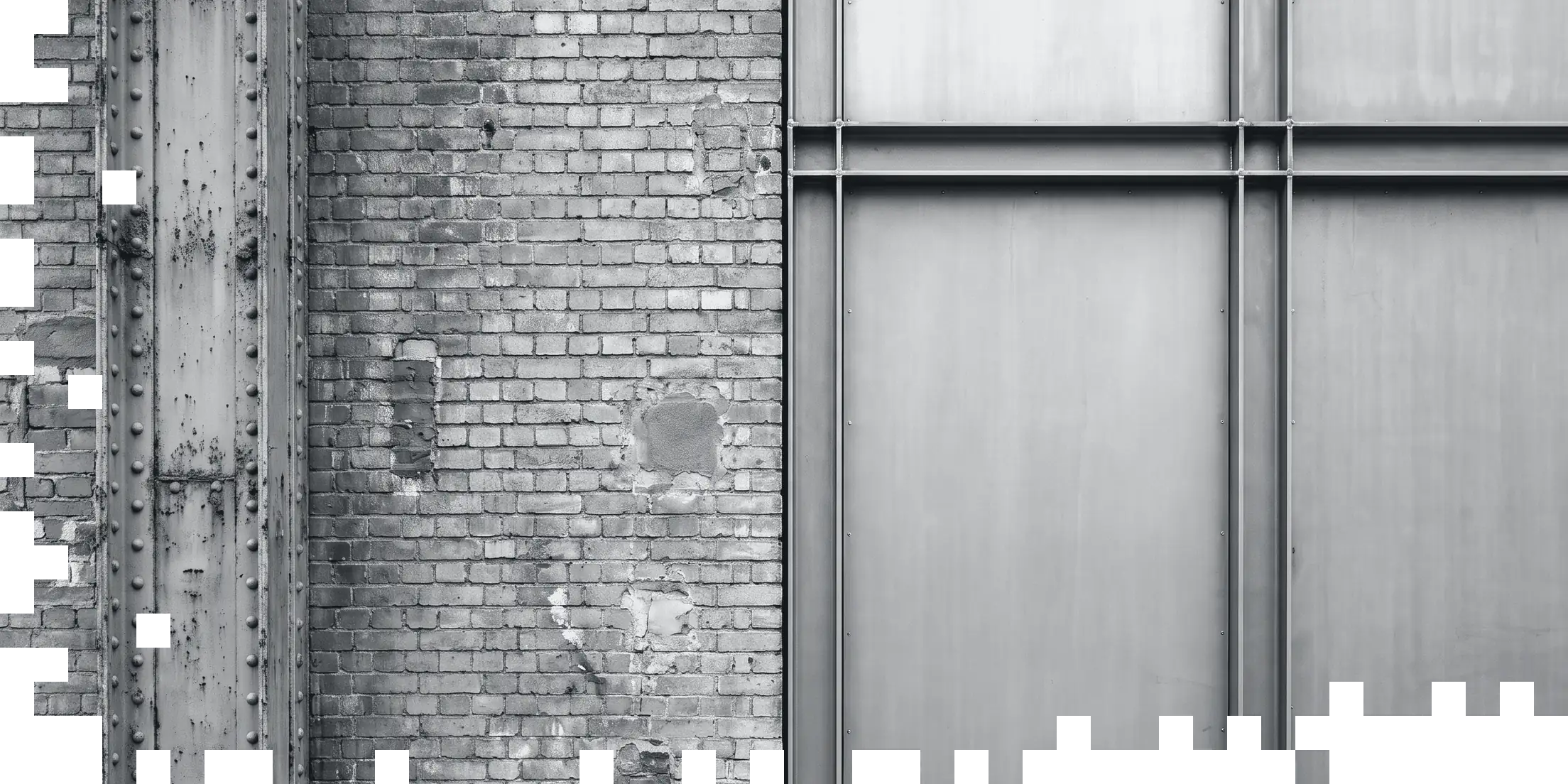 Fassade an der Nahtstelle zwischen Bestand und Neubau: links eine genietete Stahlstütze und mehrfach geflicktes Ziegelmauerwerk, rechts eine neu gesetzte Rasterfassade aus Stahl und Blech. Die linke und die untere Bildkante lösen sich in einzelne quadratische Module auf.